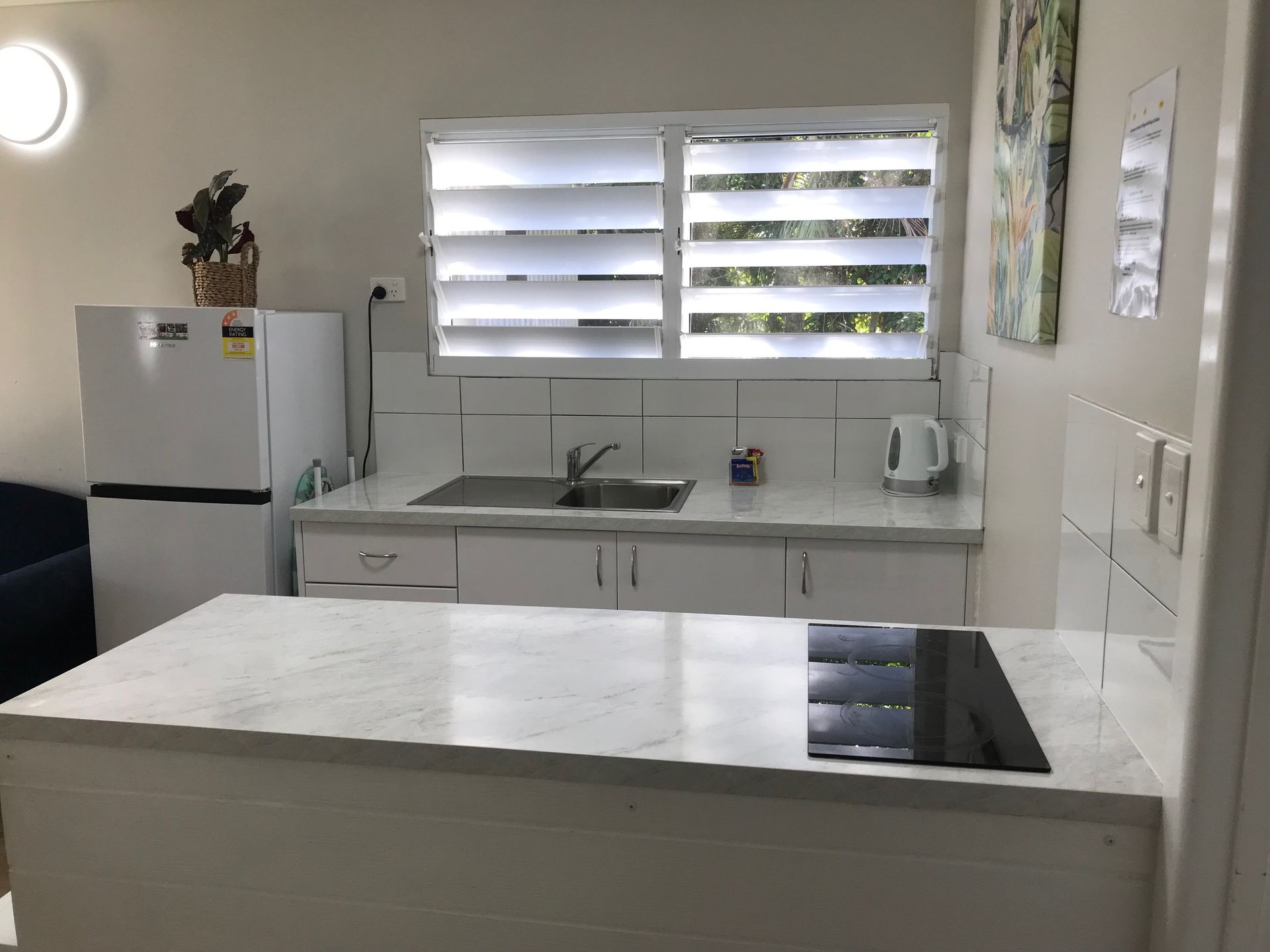 A Kitchen With A Refrigerator, Sink, Stove And Window — Bush Village Holiday Cabins In Cannonvale, QLD