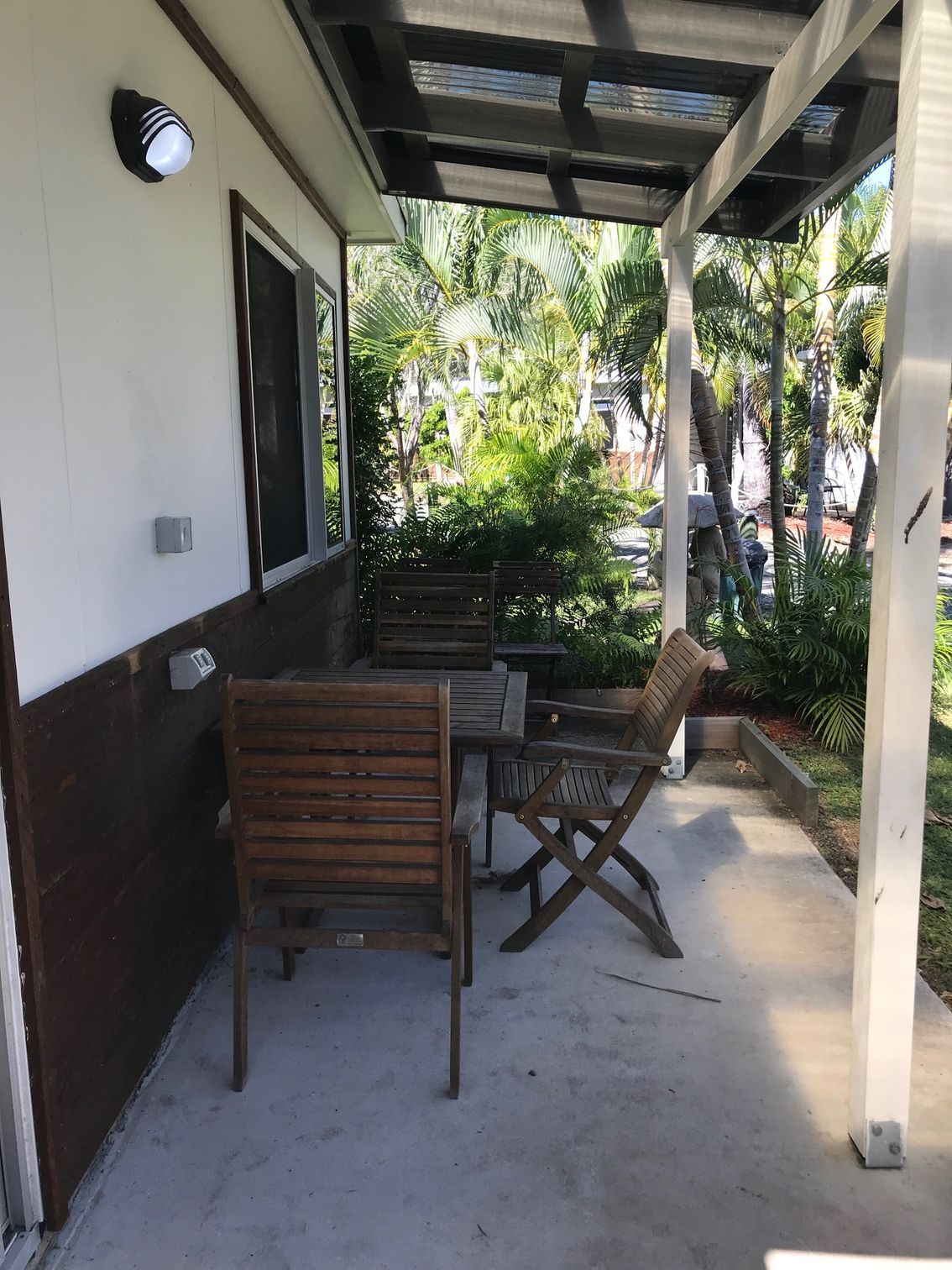 A Patio With A Table And Chairs Under A Canopy — Bush Village Holiday Cabins In Cannonvale, QLD