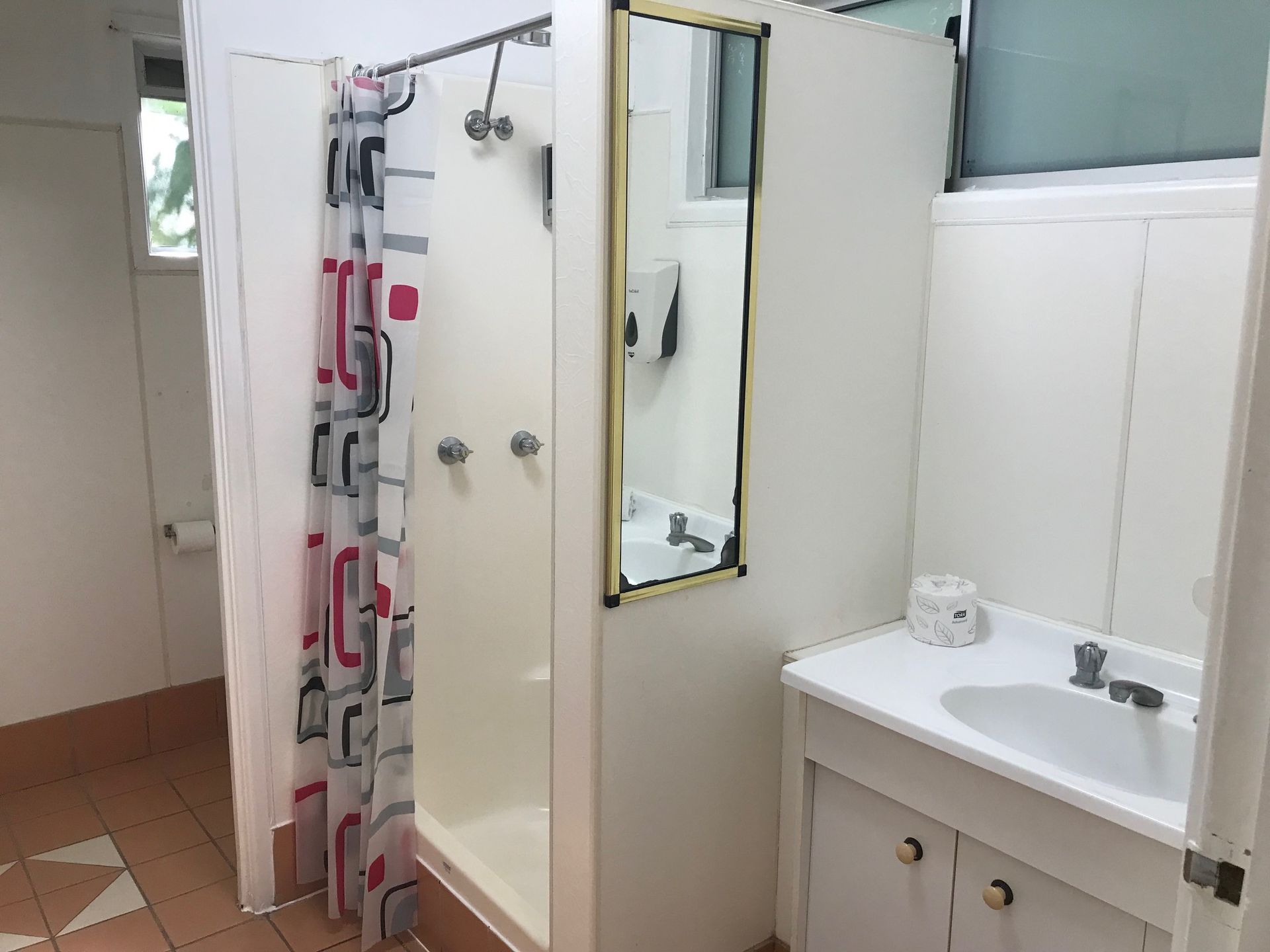 A Bathroom With A Sink , Shower And Mirror — Bush Village Holiday Cabins In Cannonvale, QLD