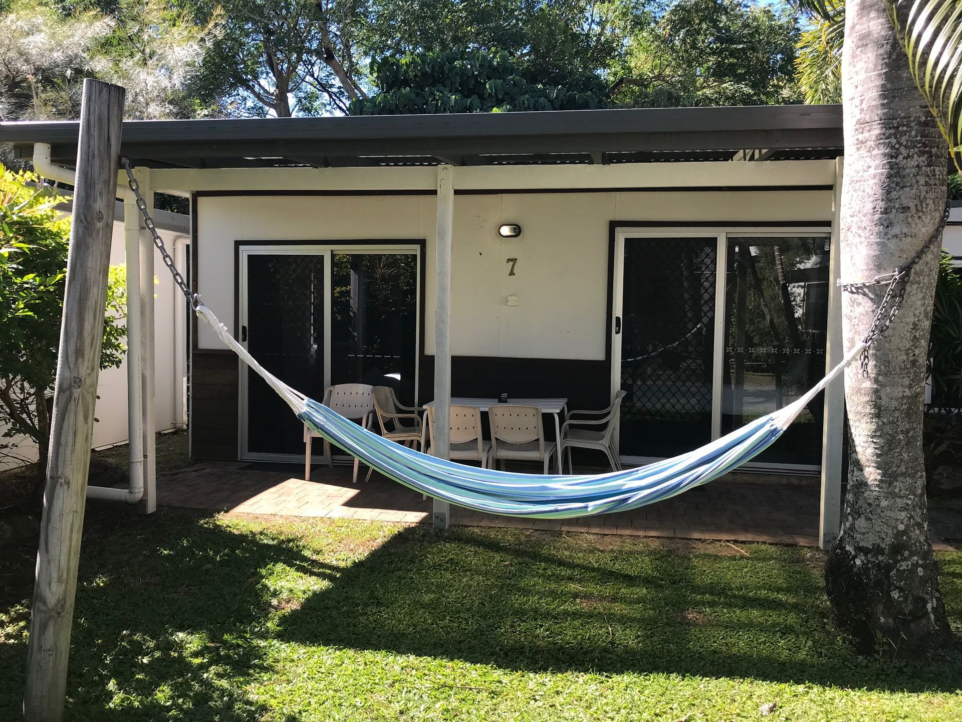 A Hammock Is Hanging From A Tree In Front Of A House — Bush Village Holiday Cabins In Cannonvale, QLD