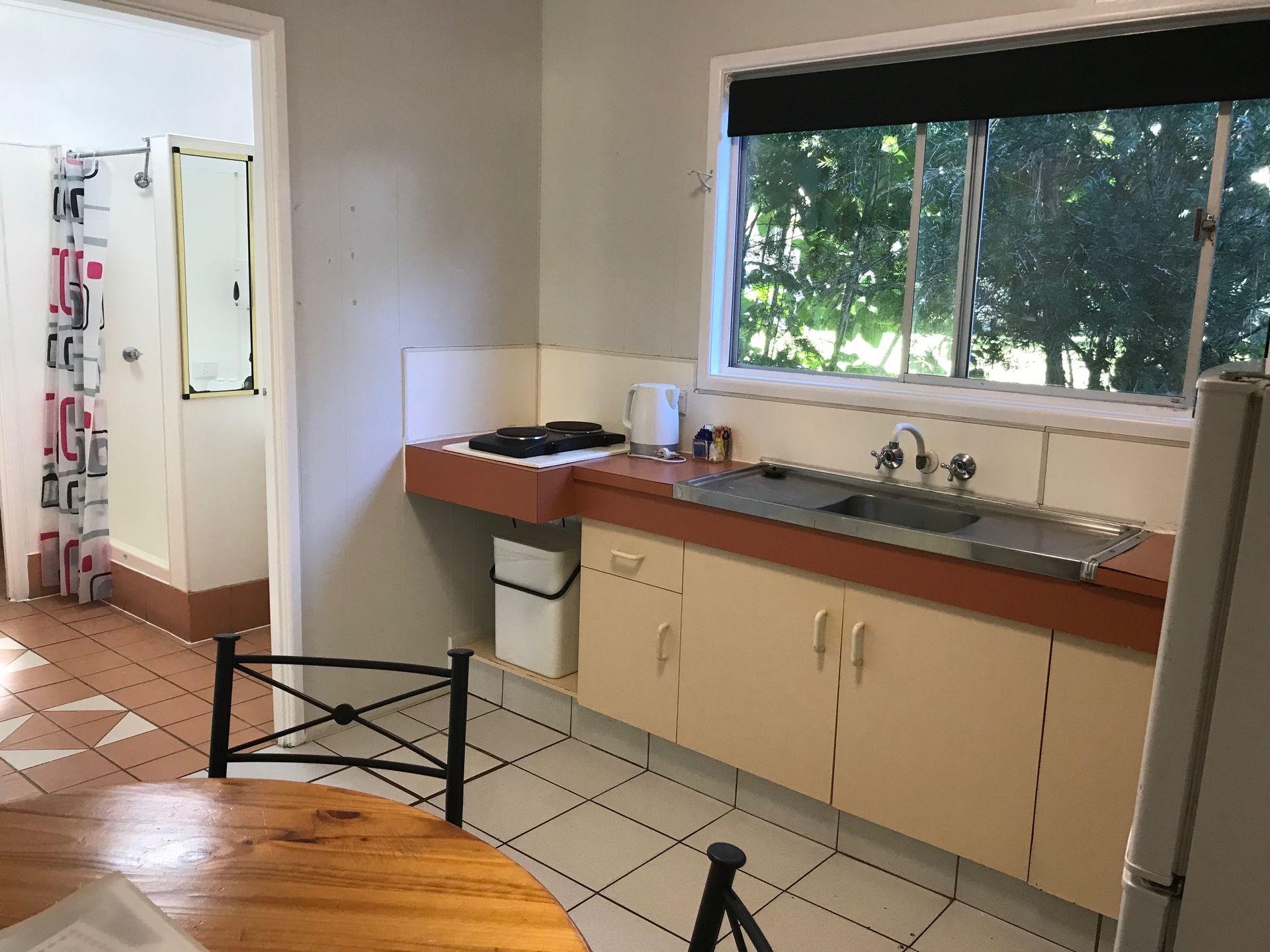 A Kitchen With A Table And Chairs And A Sink — Bush Village Holiday Cabins In Cannonvale, QLD