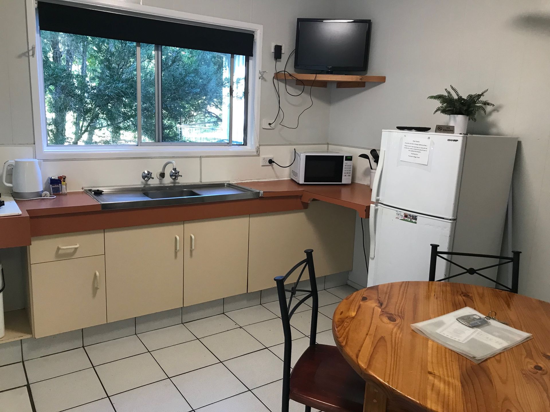 A Kitchen With A Table And Chairs And A Refrigerator — Bush Village Holiday Cabins In Cannonvale, QLD