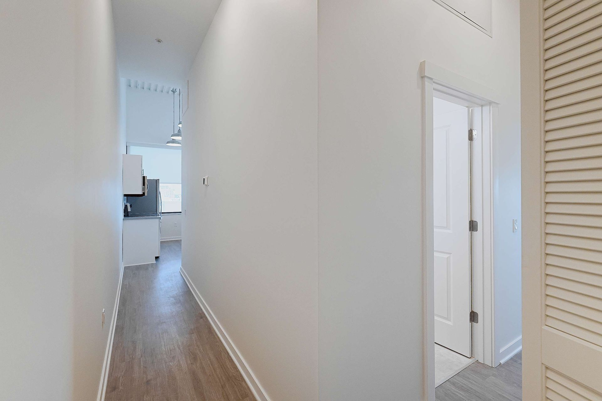 A long hallway leading to a kitchen and a bathroom in a house.