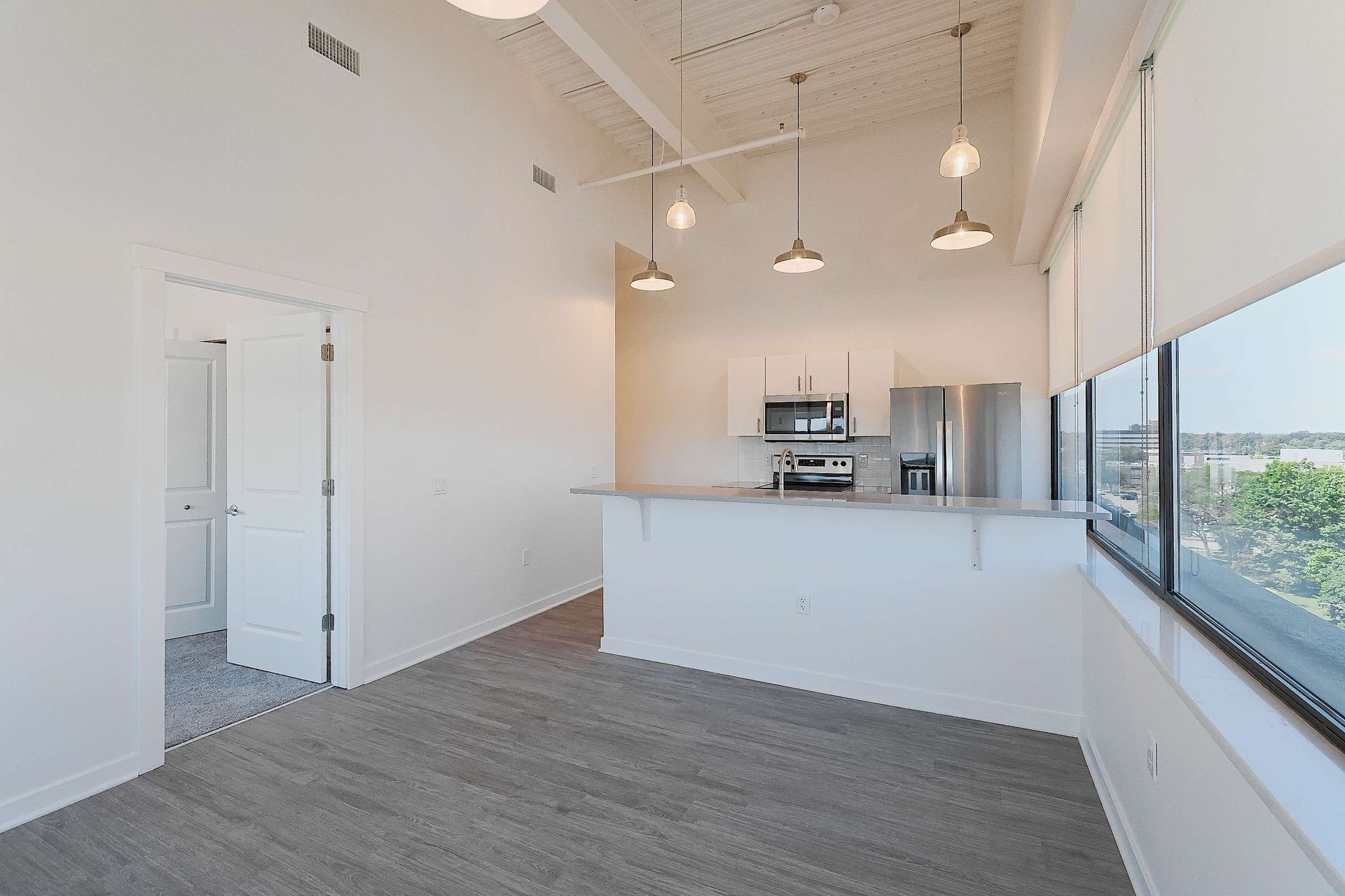 An empty apartment with a kitchen and a large window