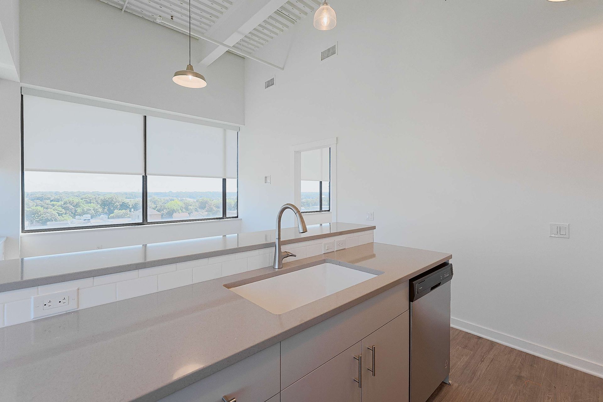 A kitchen with a sink , dishwasher , and large windows.