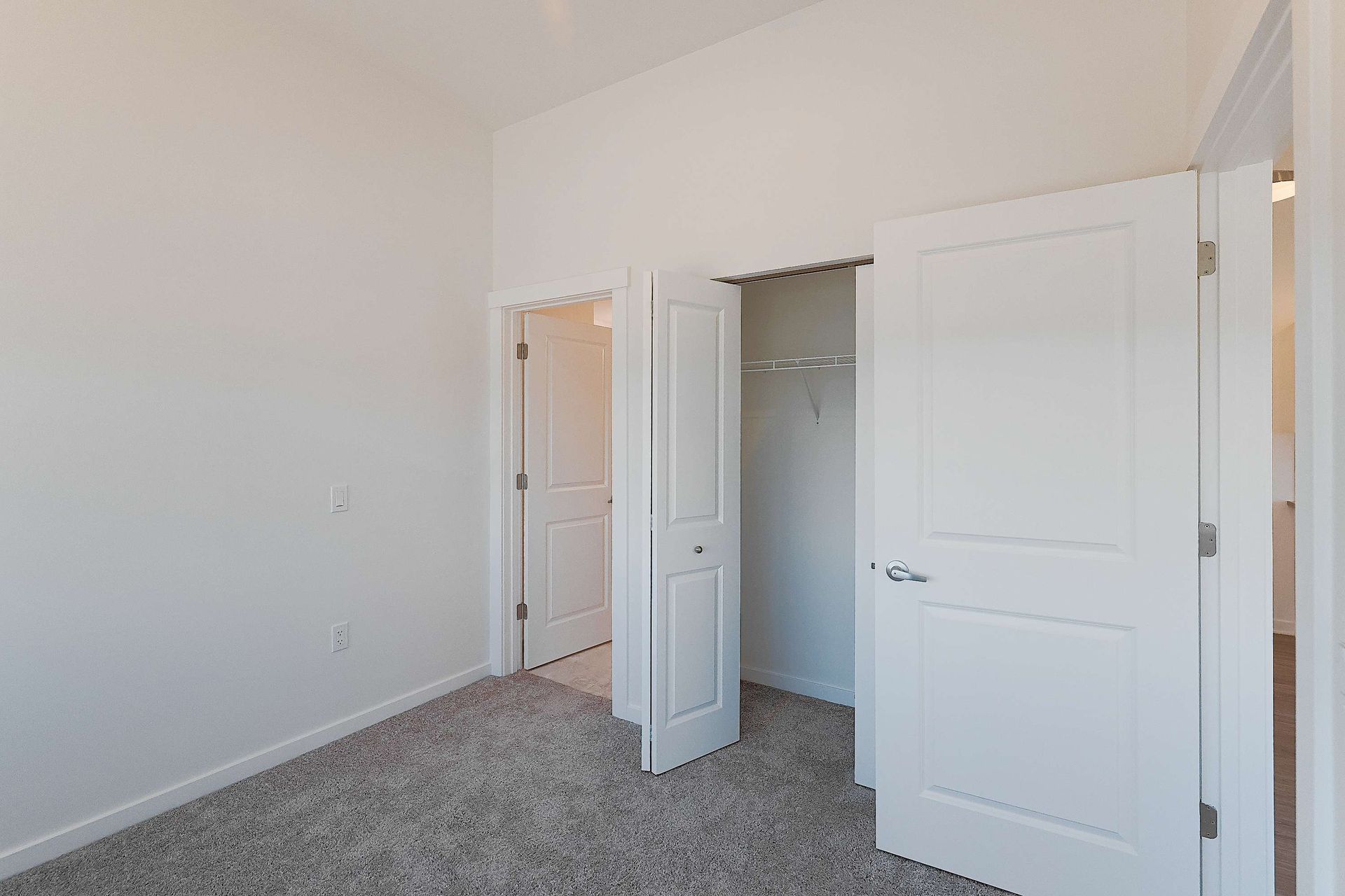 An empty bedroom with a closet and a carpeted floor.