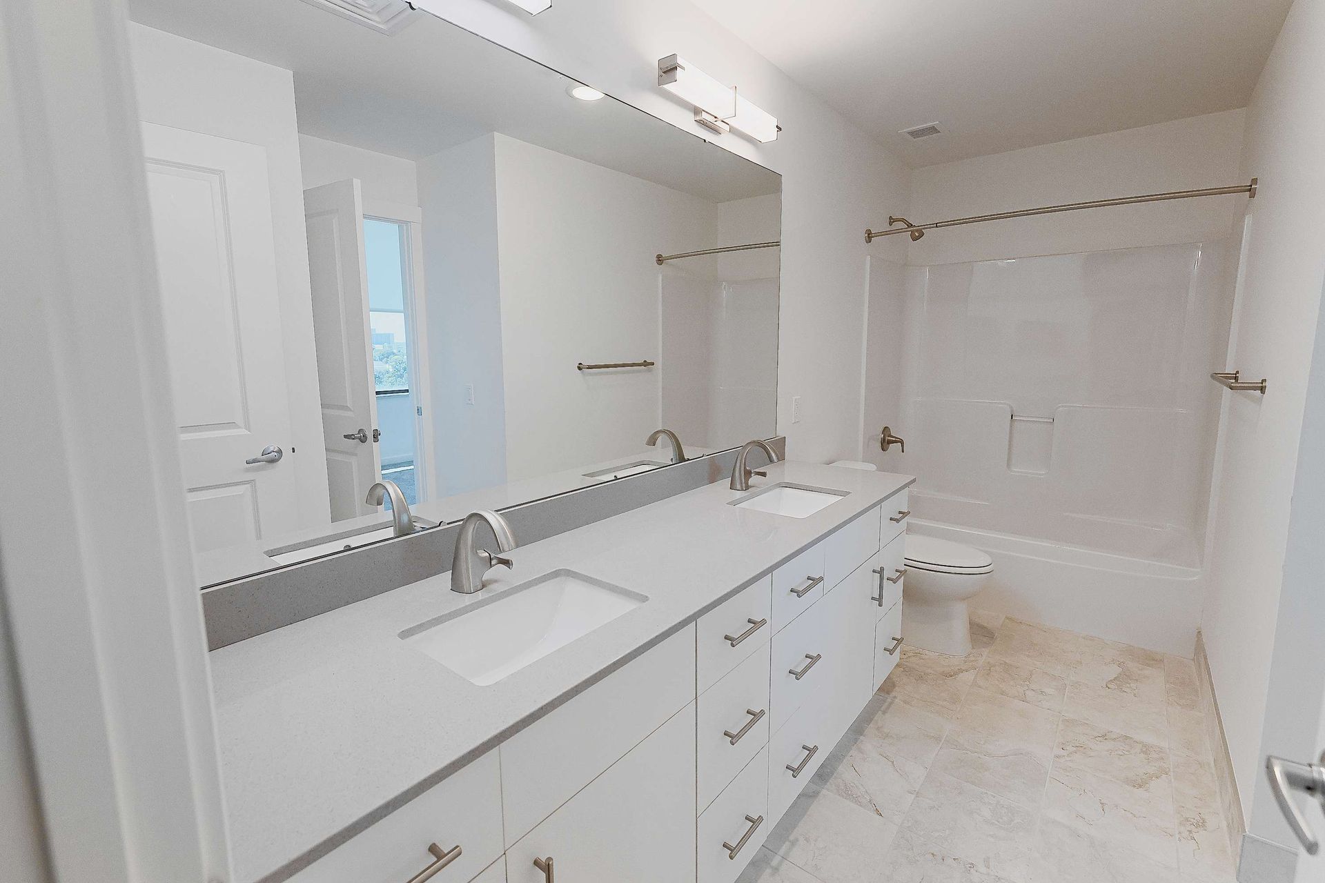 A bathroom with two sinks , a toilet , and a large mirror.