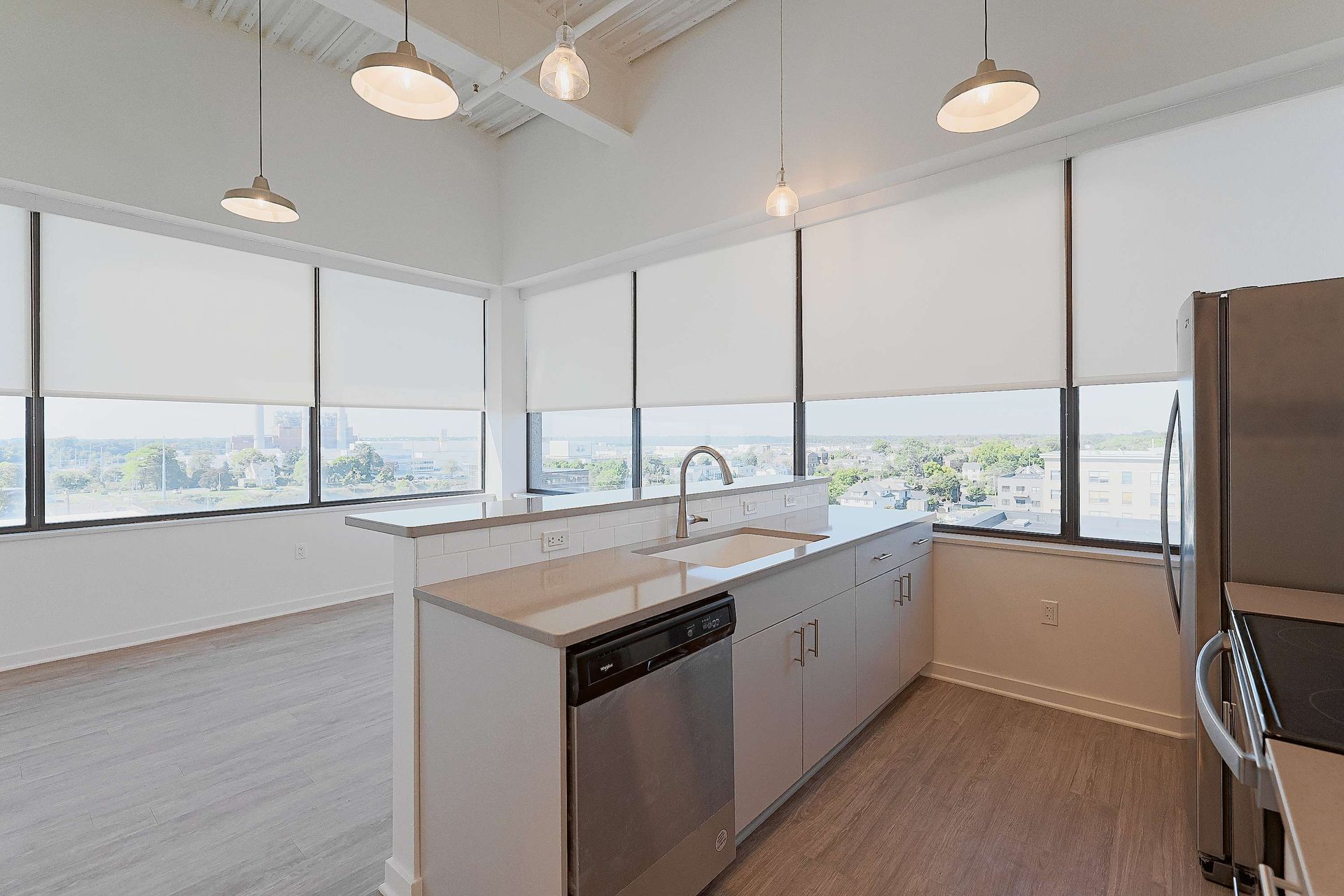 A kitchen with a sink , refrigerator , dishwasher , and lots of windows.