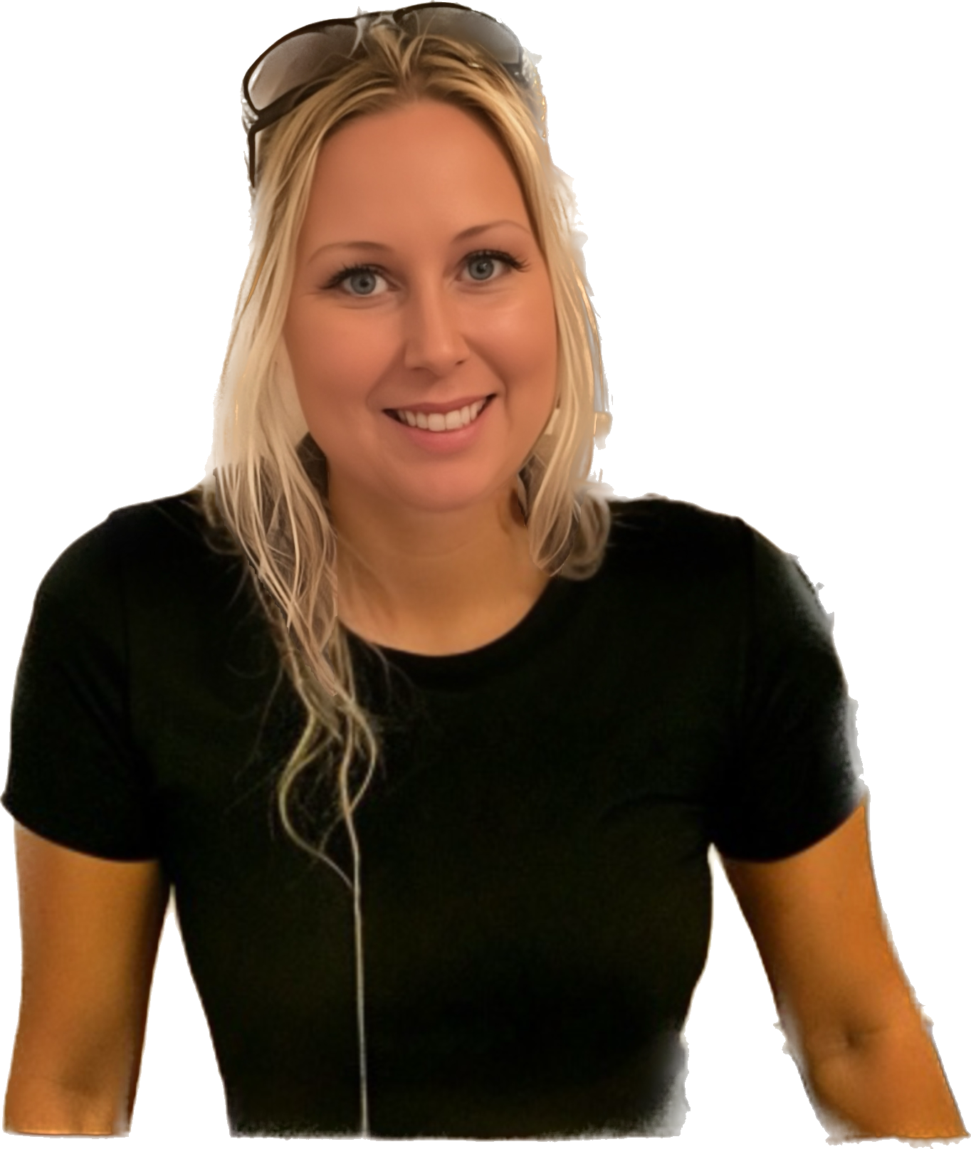 Woman with blonde hair smiles, wearing a white blazer over a black top, arms crossed.