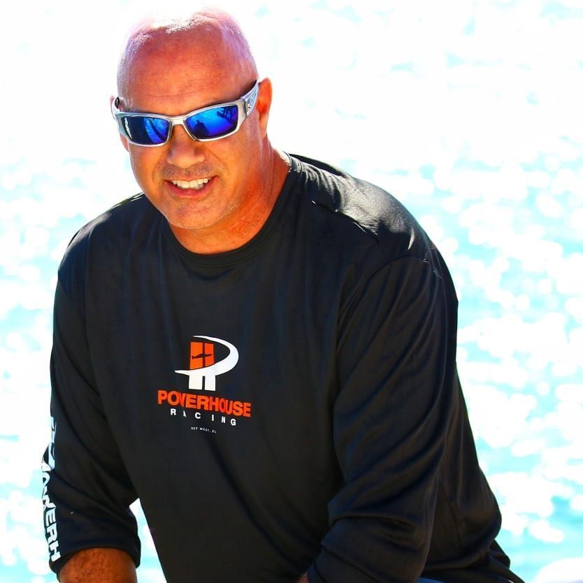 A man wearing sunglasses and a black powerhouse shirt
