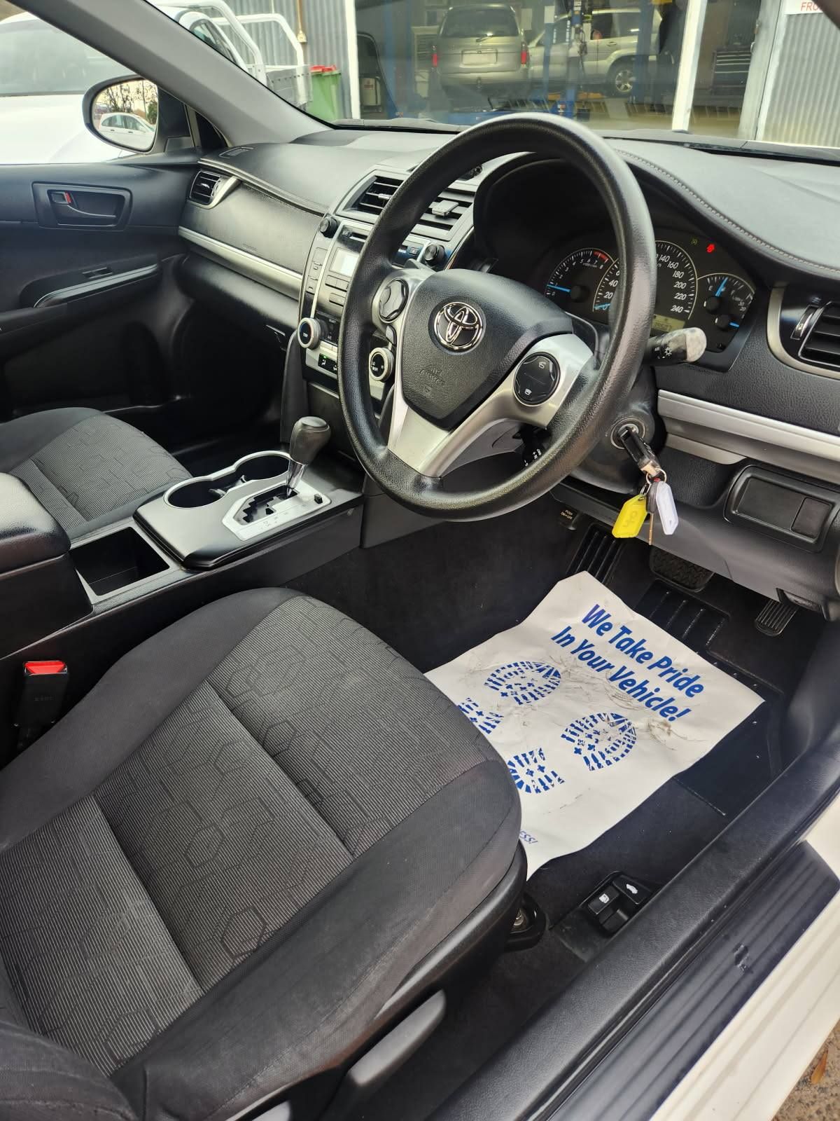 Interior of a Toyota Camry: black seats, dashboard, and steering wheel. A