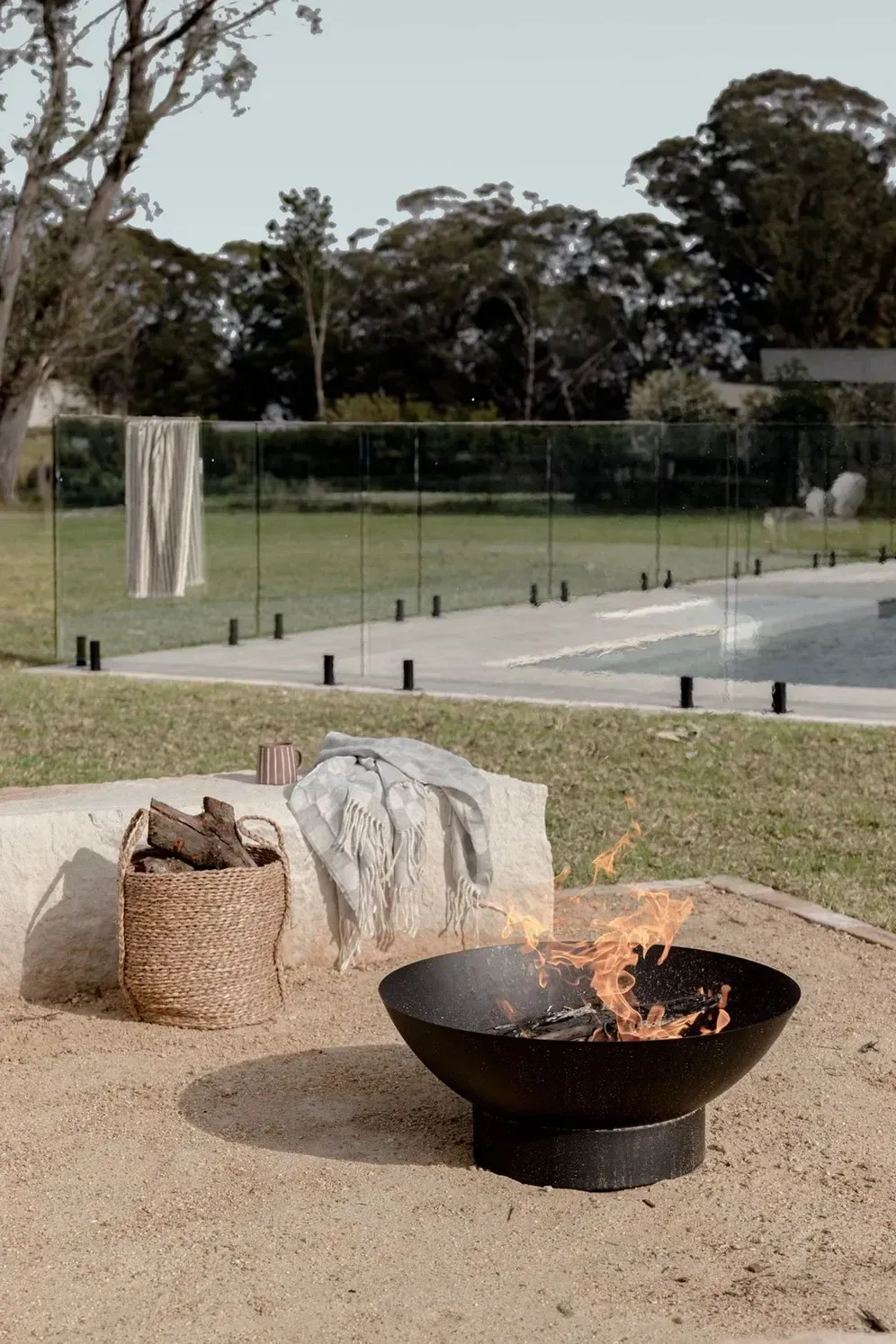A Fire Pit Is Sitting Next to A Pool in A Backyard — Billabong Pool Co in Smeaton Grange, NSW