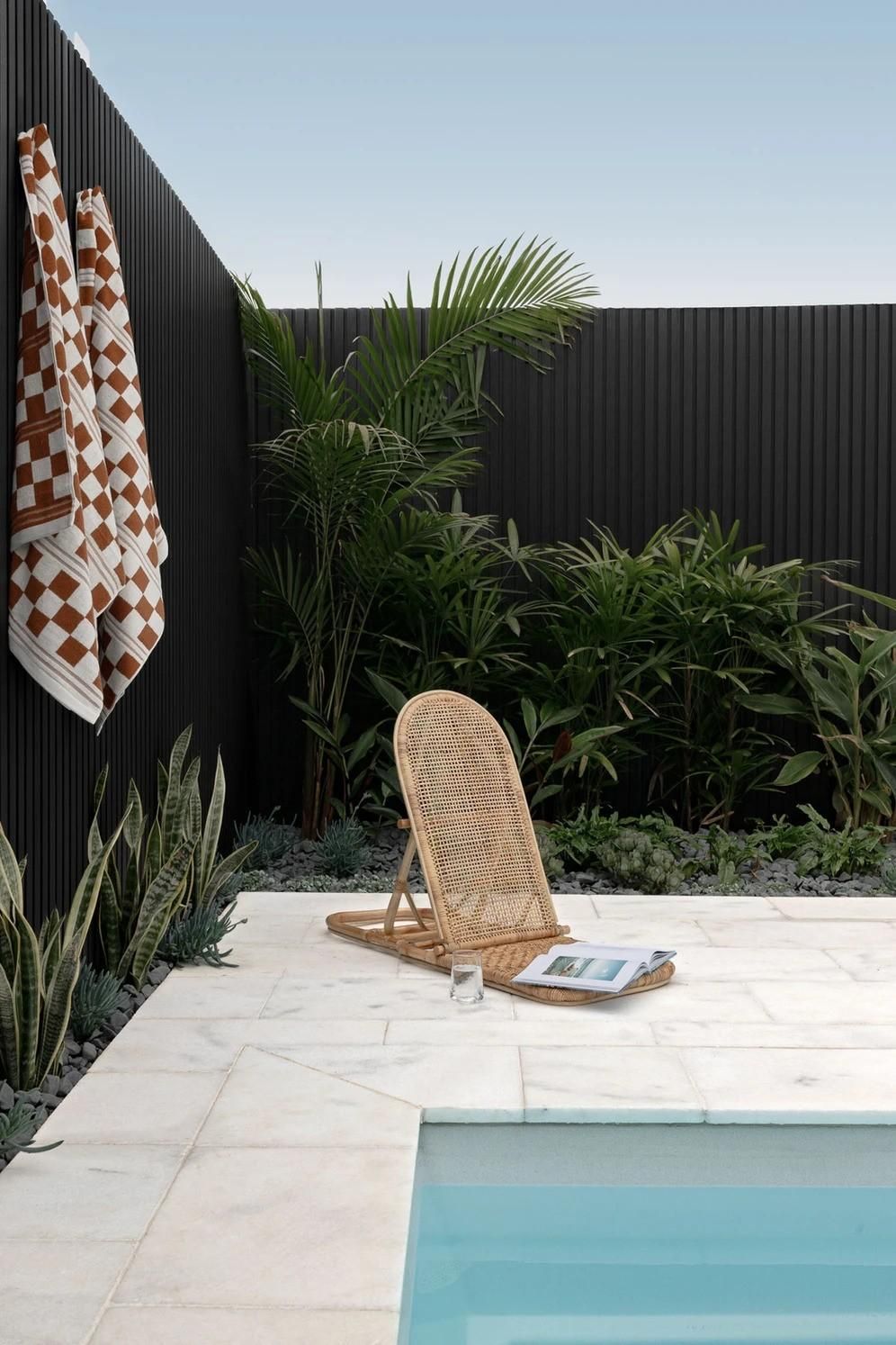 A Wicker Chair Is Sitting Next to A Swimming Pool — Billabong Pool Co in Smeaton Grange, NSW