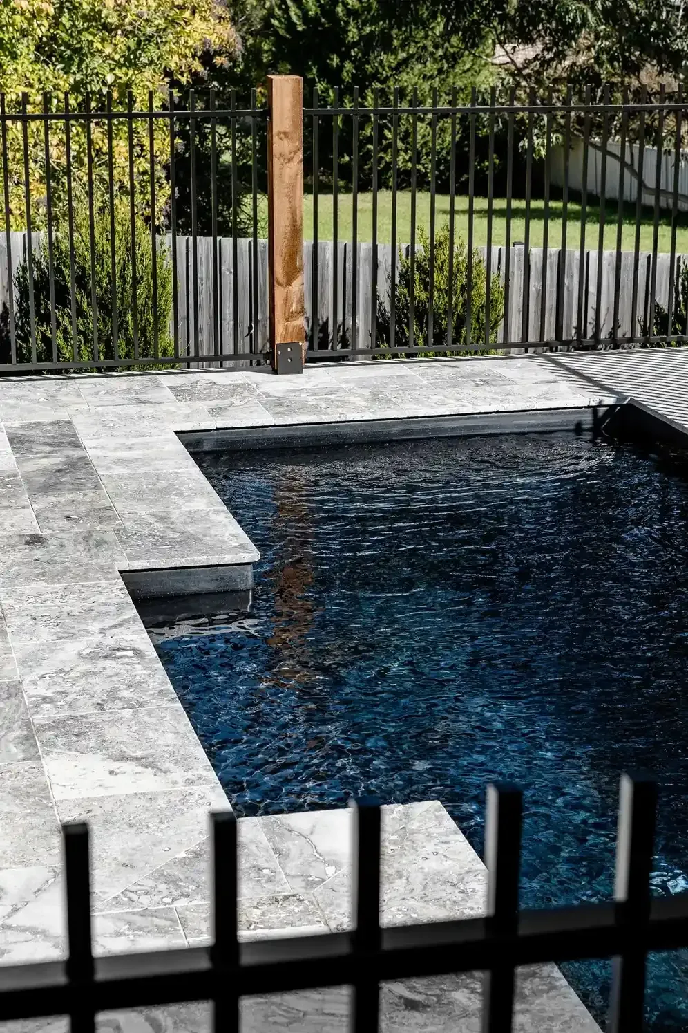 A Fence Surrounds a Swimming Pool in A Backyard — Billabong Pool Co in Smeaton Grange, NSW