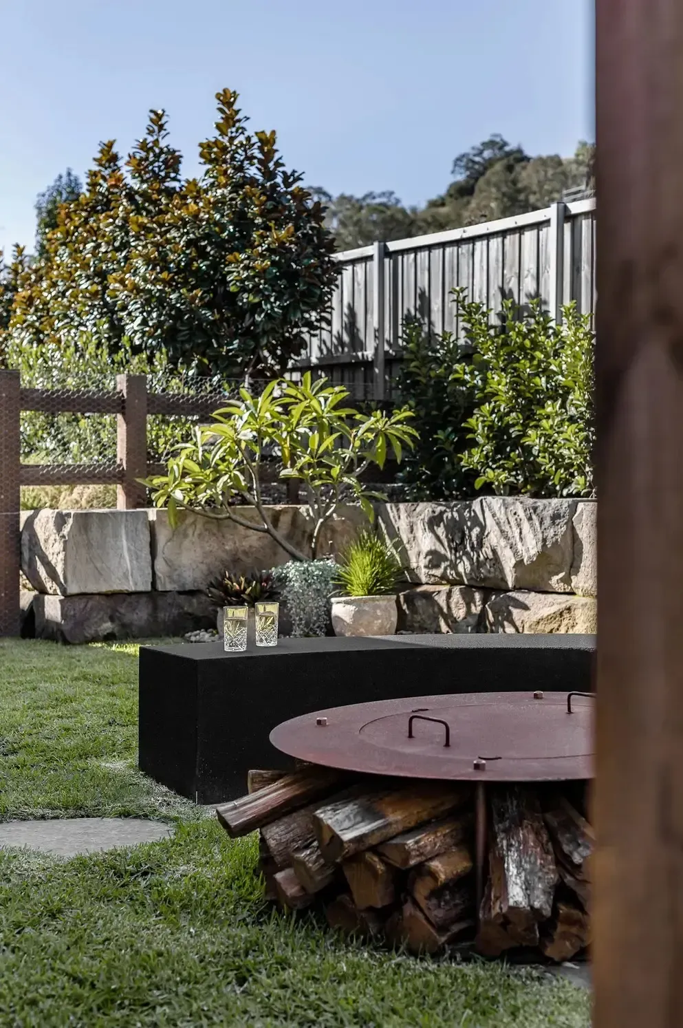 A Fire Pit Filled with Logs in A Backyard — Billabong Pool Co in Smeaton Grange, NSW