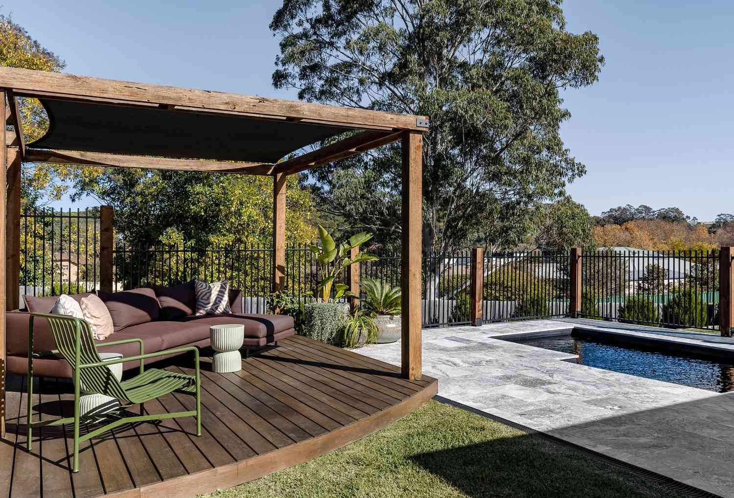 A Wooden Deck with A Couch Next to A Pool — Billabong Pool Co in Smeaton Grange, NSW
