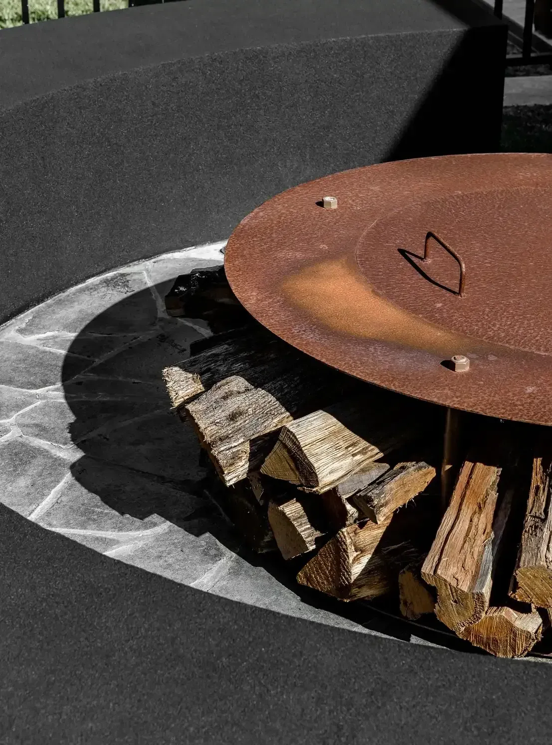 A Rusty Fire Pit Filled with Logs on A Patio — Billabong Pool Co in Smeaton Grange, NSW