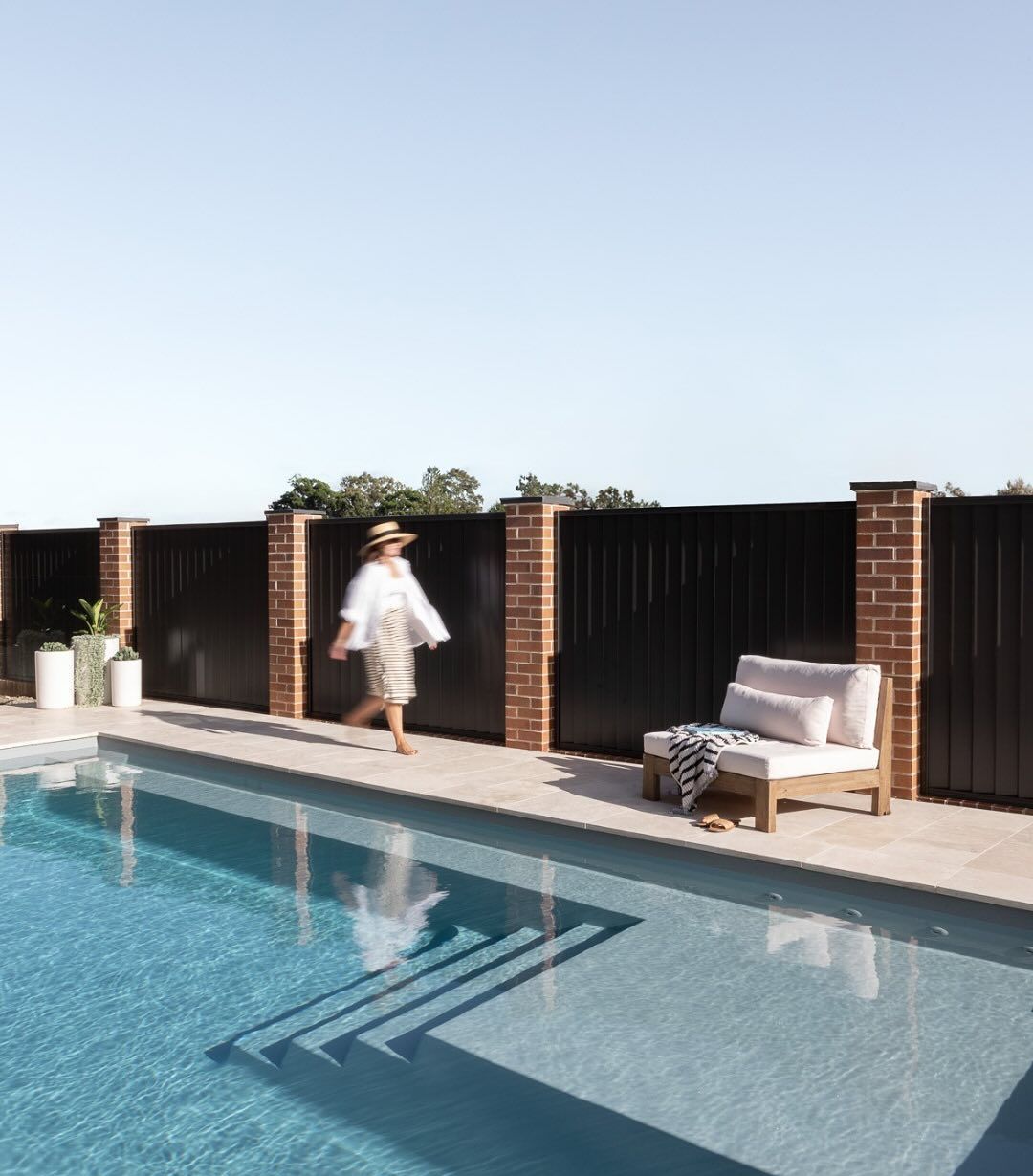 a woman is walking next to a pool — Billabong Pool Co in Smeaton Grange, NSW