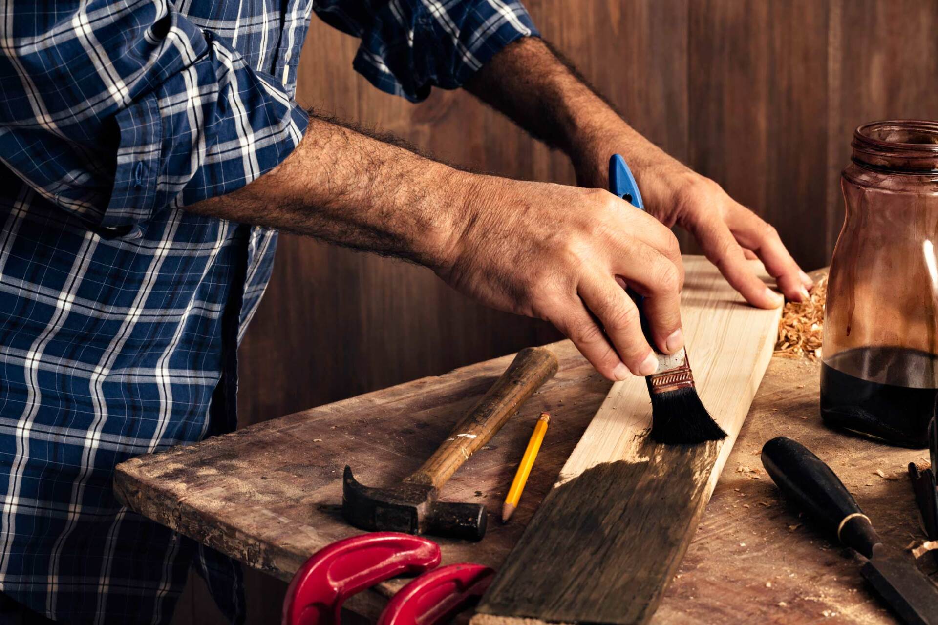 Male Carpenter Stain Dying Lumber Plank In Home Workshop - Warren, MI - Maple Lane Pest Control