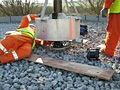 A man in orange pants is laying on the ground next to a wooden board.