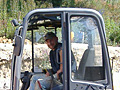 A man is sitting in the driver 's seat of a small excavator.