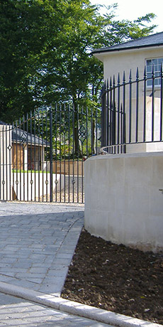 A fence surrounds a driveway leading to a house.