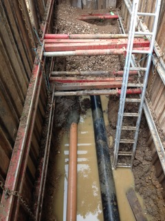 Davis Groundworks | A ladder is sitting in a muddy trench next to a pipe.