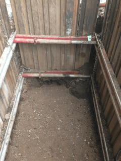 Davis Groundworks | A hole in the ground with a wooden fence in the background.