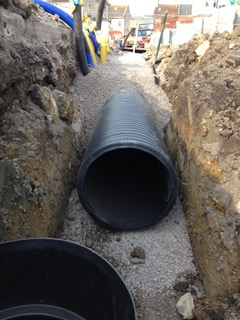 Davis Groundworks | A large black pipe is laying in the dirt in a trench.