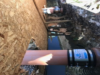 Davis Groundworks | A pipe is being installed in the ground next to a wall.