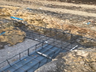 A bridge is being built in the dirt next to a rock wall.