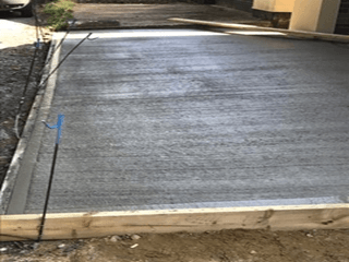 A concrete driveway is being built in front of a house.