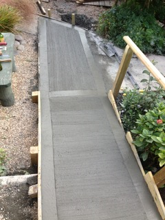 A concrete walkway is being built in a garden
