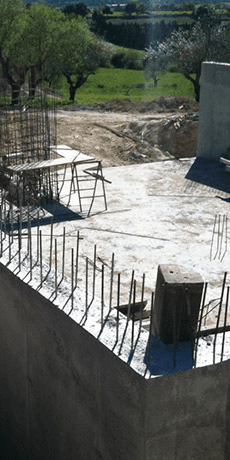 A building under construction with a fence around it and a field in the background.