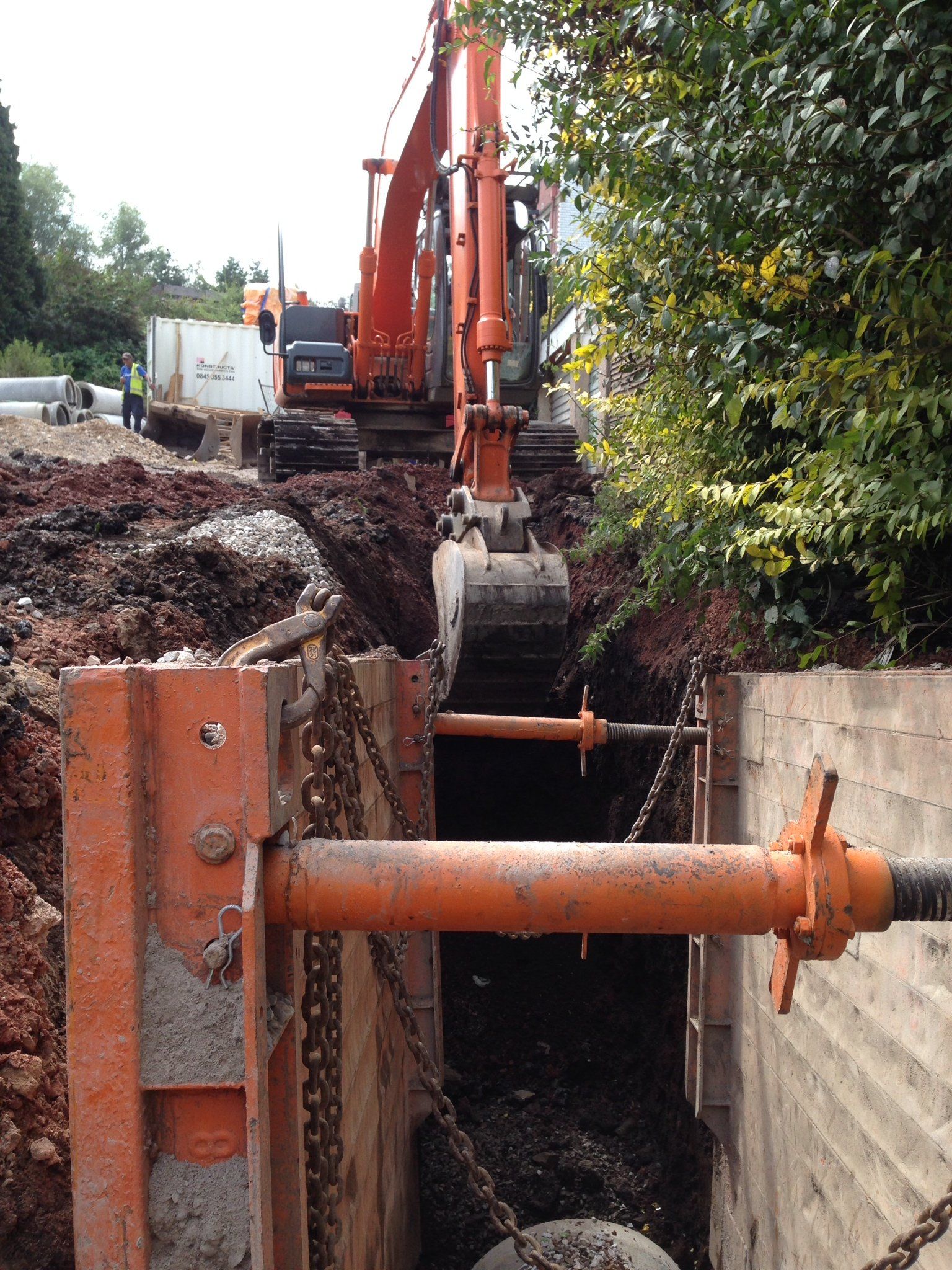 A large orange excavator is digging a hole in the ground.
