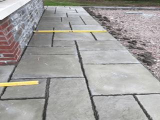 A sidewalk is being measured with a yellow tape measure.