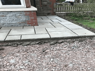 A stone walkway is being built in front of a brick building.