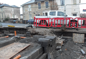 A white truck is parked behind a red and white fence