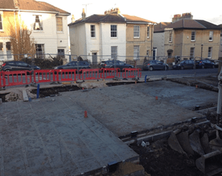 A construction site with cars parked in front of houses