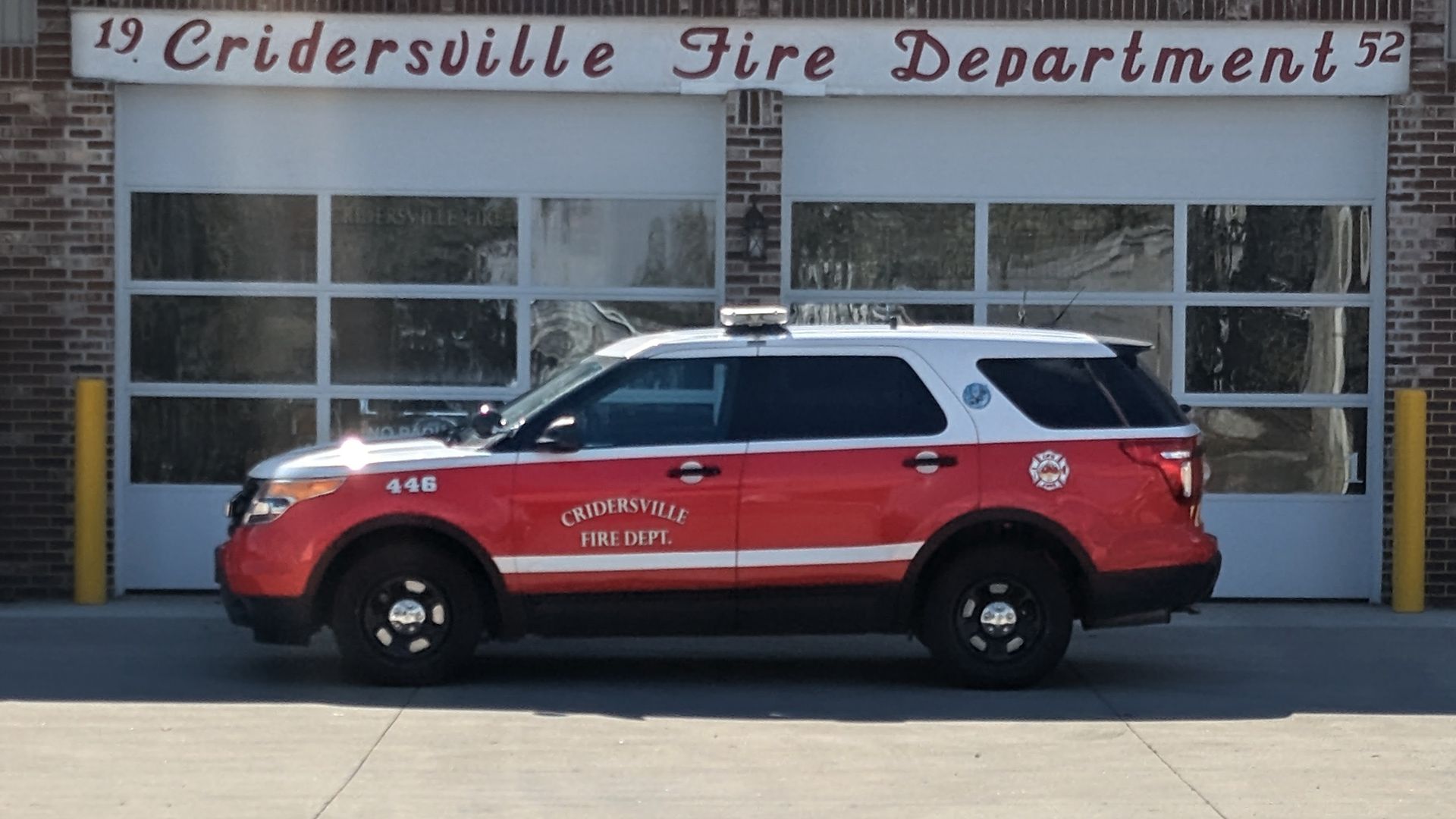 Red and white fire department SUV parked outside the station.