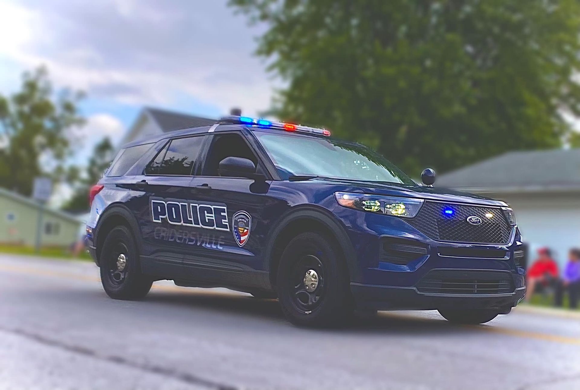 Dark blue police SUV with flashing lights, parked on a street.