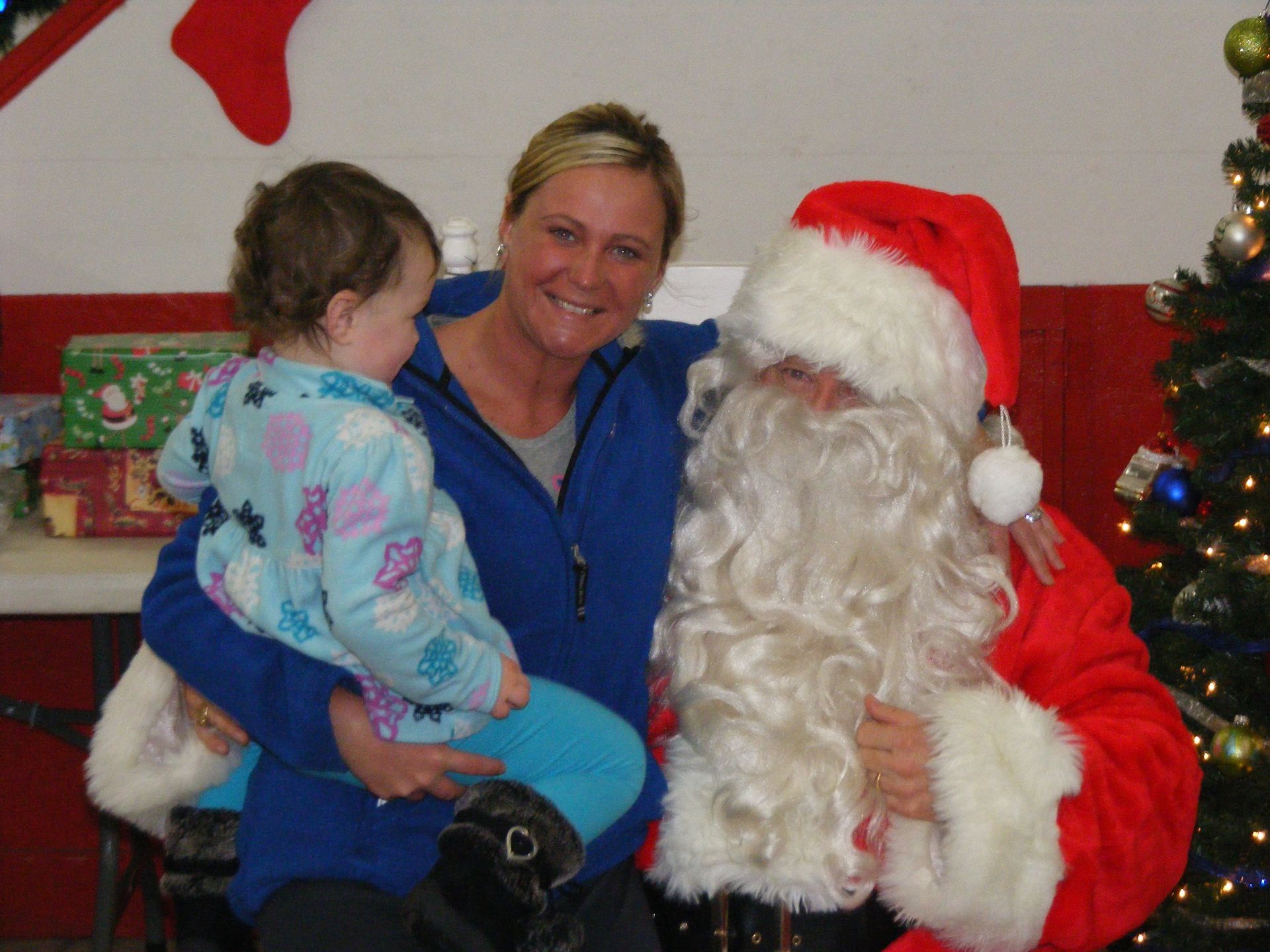 Woman and child with Santa Claus; Christmas tree in background.