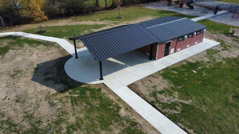 Green dragon-shaped spring rider on a wood-chip playground. Red springs and metal frame.