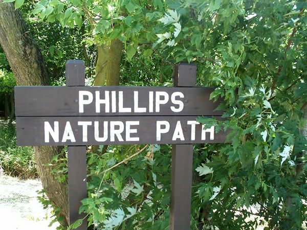 Brown sign: Phillips Nature Path in a green, natural setting.