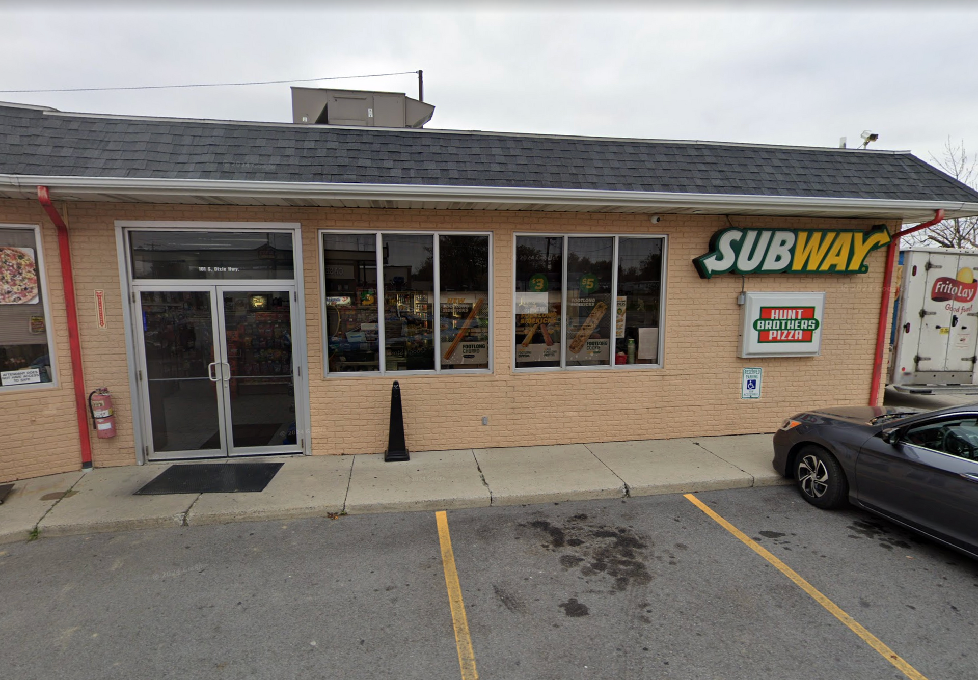 Subway restaurant with a black door, large windows, and a parking space.