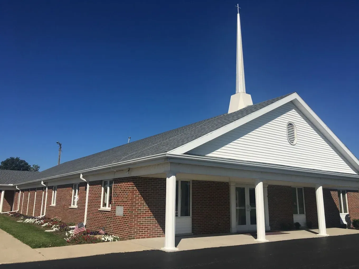 Brick church with white steeple, gray roof, and blue sky.