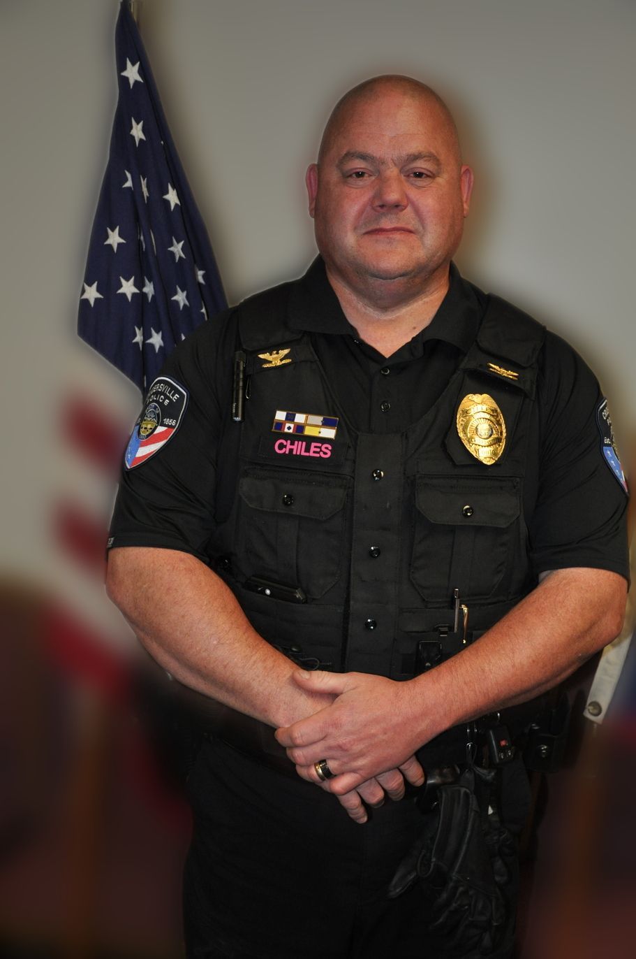 Police car with flashing red and blue lights, parked at night in front of a house.