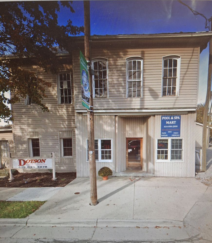 Two-story building with a spa. Gray wooden exterior, small sign, and a pole in front.