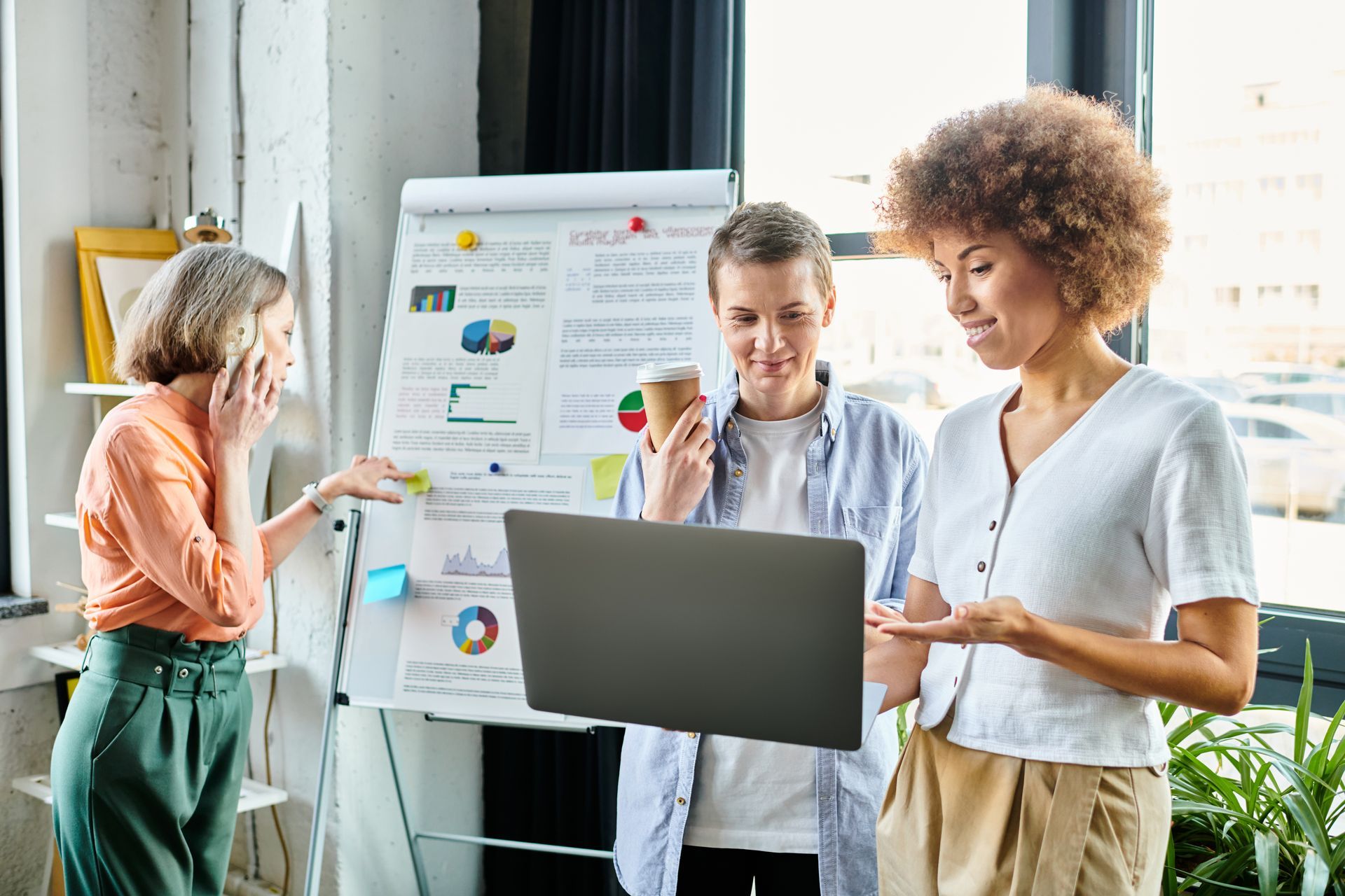 Colleagues discussing a presentation beside a laptop and flip chart in a bright office