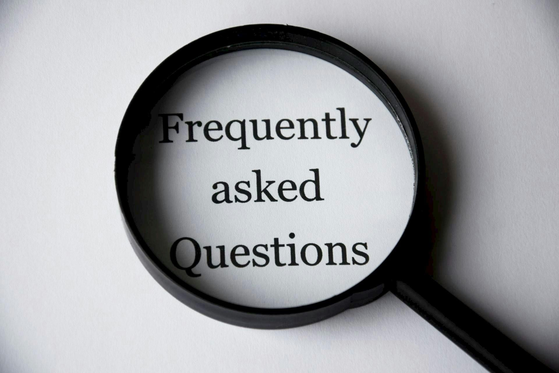 Magnifying glass over the words “Frequently asked Questions” on a white background